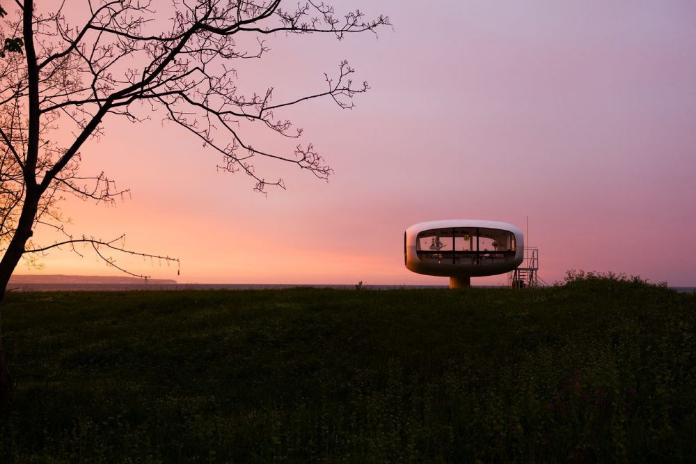 Ufo von Ulrich MÃ¼ther 
Binz RÃ¼gen
Schlüsselwörter: Architektur Moderne futuristisch schwebend geschwungen Betonschalenbau rund weich transparent SehenswÃ¼rdigkeit Ufo Feuer Himmel orange gelb Sonnenuntergang Farben Glas Beton Ostsee Ostseebad AtmosphÃ¤re Licht leuchten Abend abends menschenleer Ulrich MÃ¼